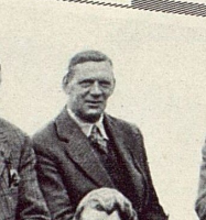 Black and white photo of a man in a coat and tie.