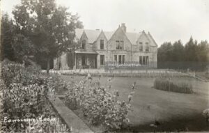 Black and white photo of a large house on a grassy field.