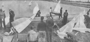 Men gathered at the beach with their model boats.