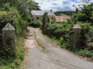 Modern photograph of stone farm buildings at the end of a road.