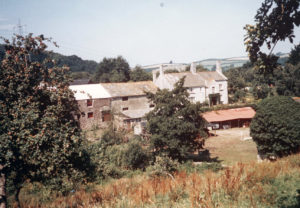 Old stone buildings adjacent to an attractive, white multi-storey house. 