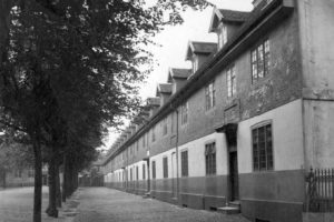 Black and white historical photo of a long building with walk-up entrances