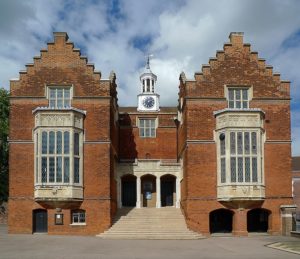 An ornate-looking red brick school with two wings and a stairway in the center.