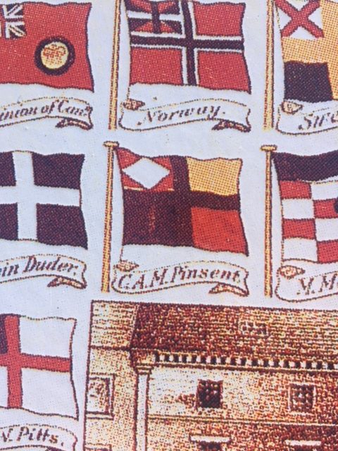 Assorted flags. In the center, C. A. M. Pinsent's flag is divided into four quarters by a black cross. In the upper left corner sits a white diamond. The other corners are yellow, black, and red.