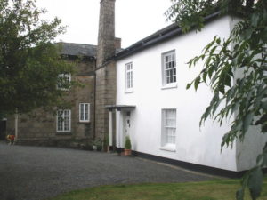 A stone building with a white painted extension.