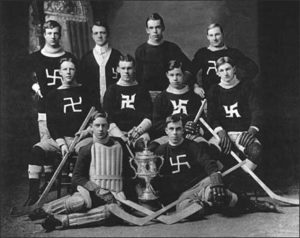 A group of hockey players wearing antiquated uniforms pose for a photograph. Their uniforms include stylized swastikas on their chests.