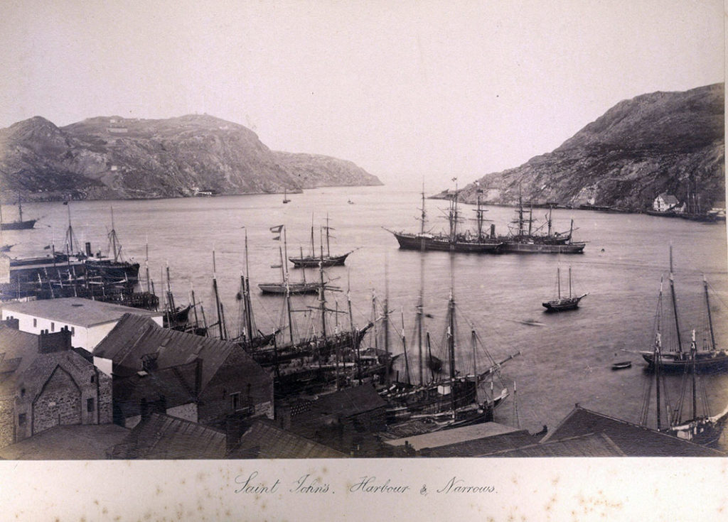 A black and white photo of sailing boats clustered in the harbour.