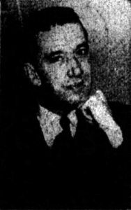 A low-resolution black and white photograph of a smiling white man with dark hair.