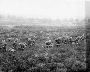 A line of WWI soldiers charging through a field.