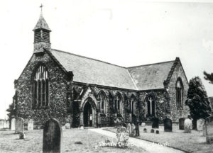 Old black and white photograph of a stone church with a graveyard out front.