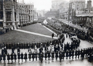 A black and white photograph of a somber-looking funeral proccession through the streets of London.