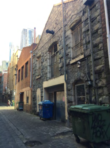 Modern photograph of an alleyway with stone buildings along one side.