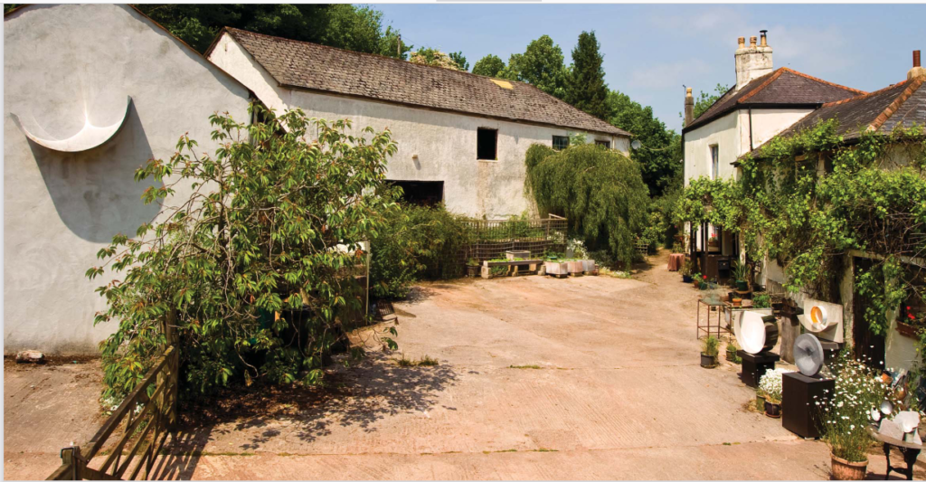 A long, white farm building in front of an empty courtyard.