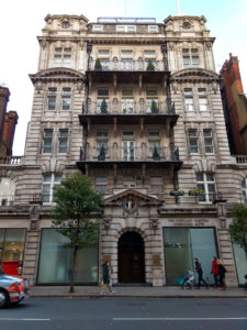Tall, ornate stone building with wrought iron balconies.