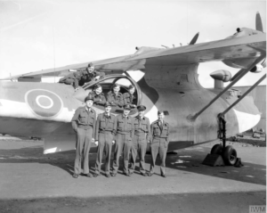 Black and white photograph of men in flight suits gathered around a plane.