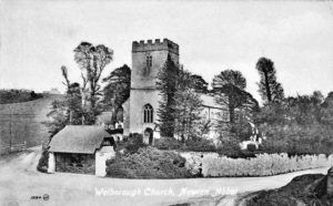 Black and white photo of a stone church nestled among trees.