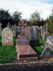 A red granite cross headstone.