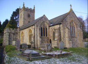 Modern photograph of a stone church and graveyard lightly dusted with snow.