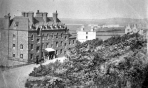 Black and white photograph of a large multi-storey building with multiple chimneys.