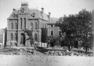 A fancy-looking multistory Victorian building photographed in black and white.
