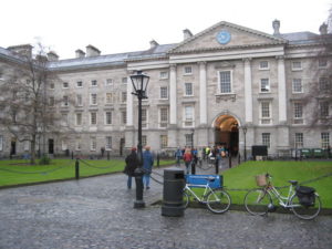 Grey stone building with columns and a grassy courtyard.