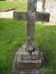 A grey stone cross in a graveyard.